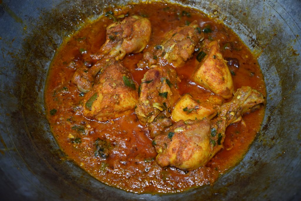 Delicious homemade chicken curry simmering in a traditional karahi with rich spices.